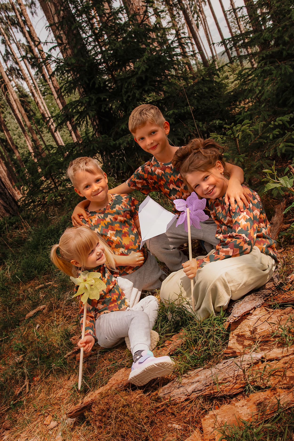 Kinder tragen Merino Kinder-Langarmshirts mit Herbst-Bergmotiv von Bellibell und spielen gemeinsam im Wald.