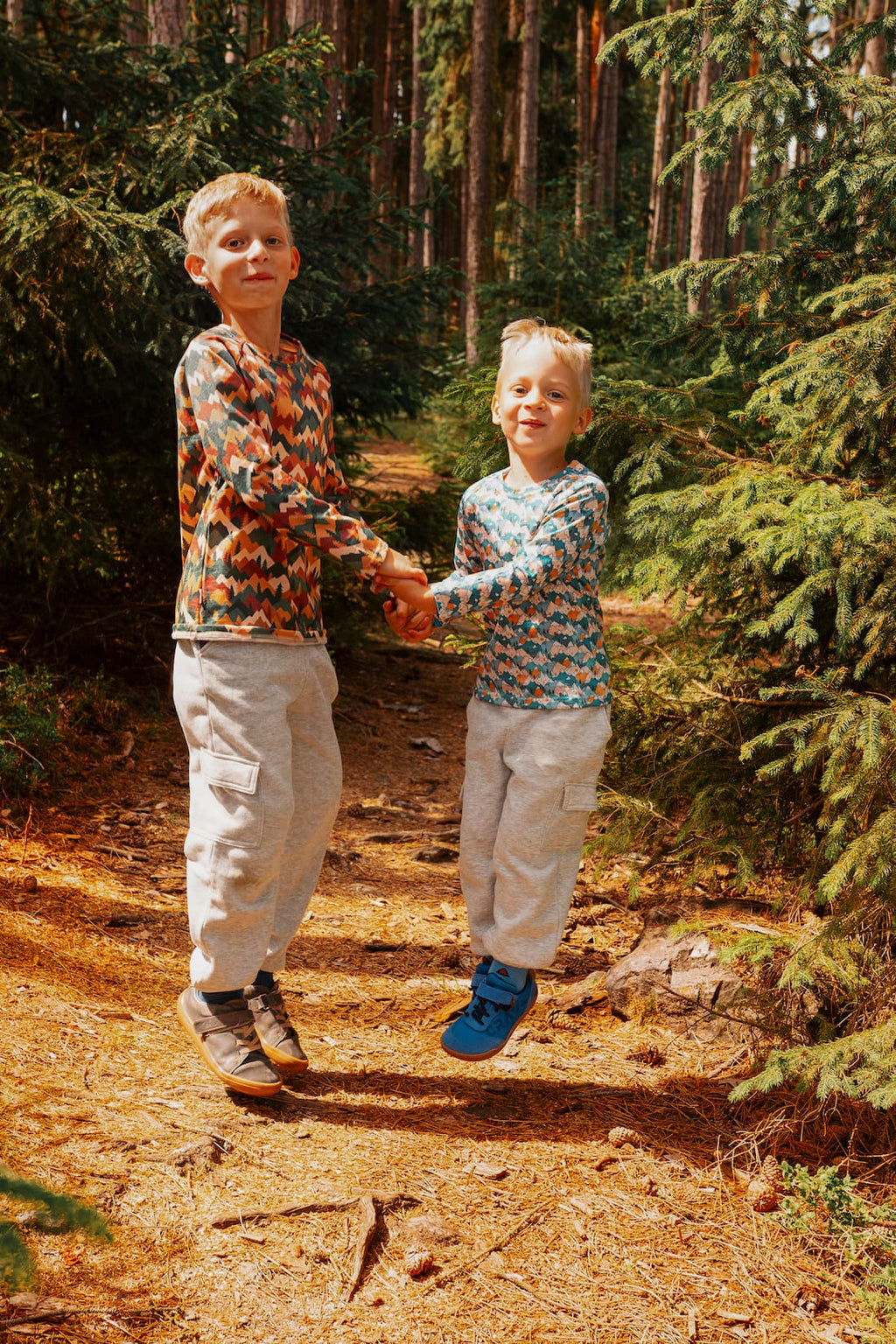 Zwei Jungen tragen Merino Kinder-Langarmshirts von Bellibell und spielen gemeinsam im Wald.