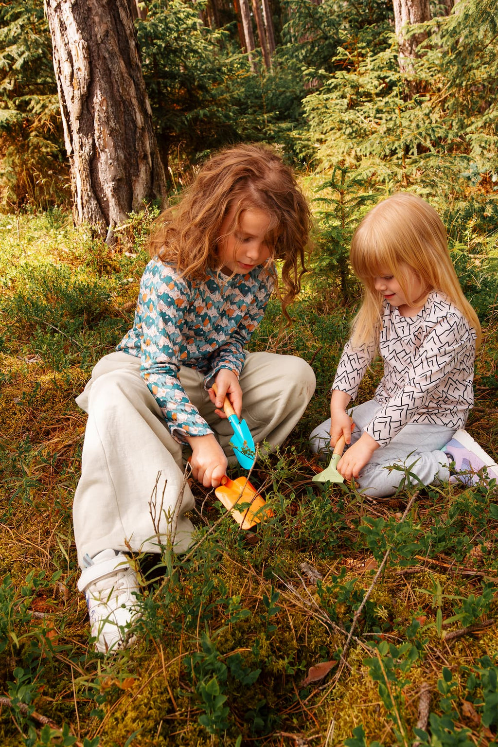 Zwei Mädchen tragen Merino Kinder-Langarmshirts von Bellibell und spielen gemeinsam im Wald.