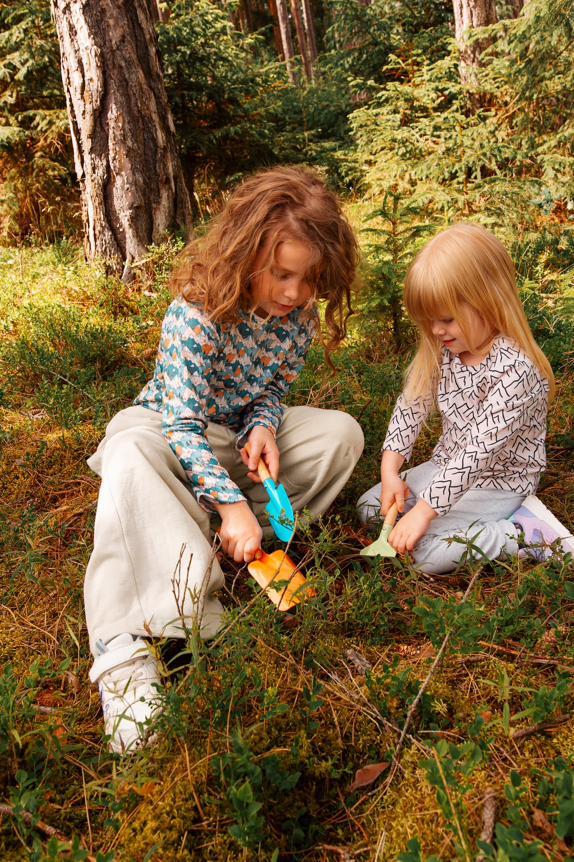 Zwei Mädchen tragen Merino Kinder-Langarmshirts von Bellibell und spielen gemeinsam im Wald.
