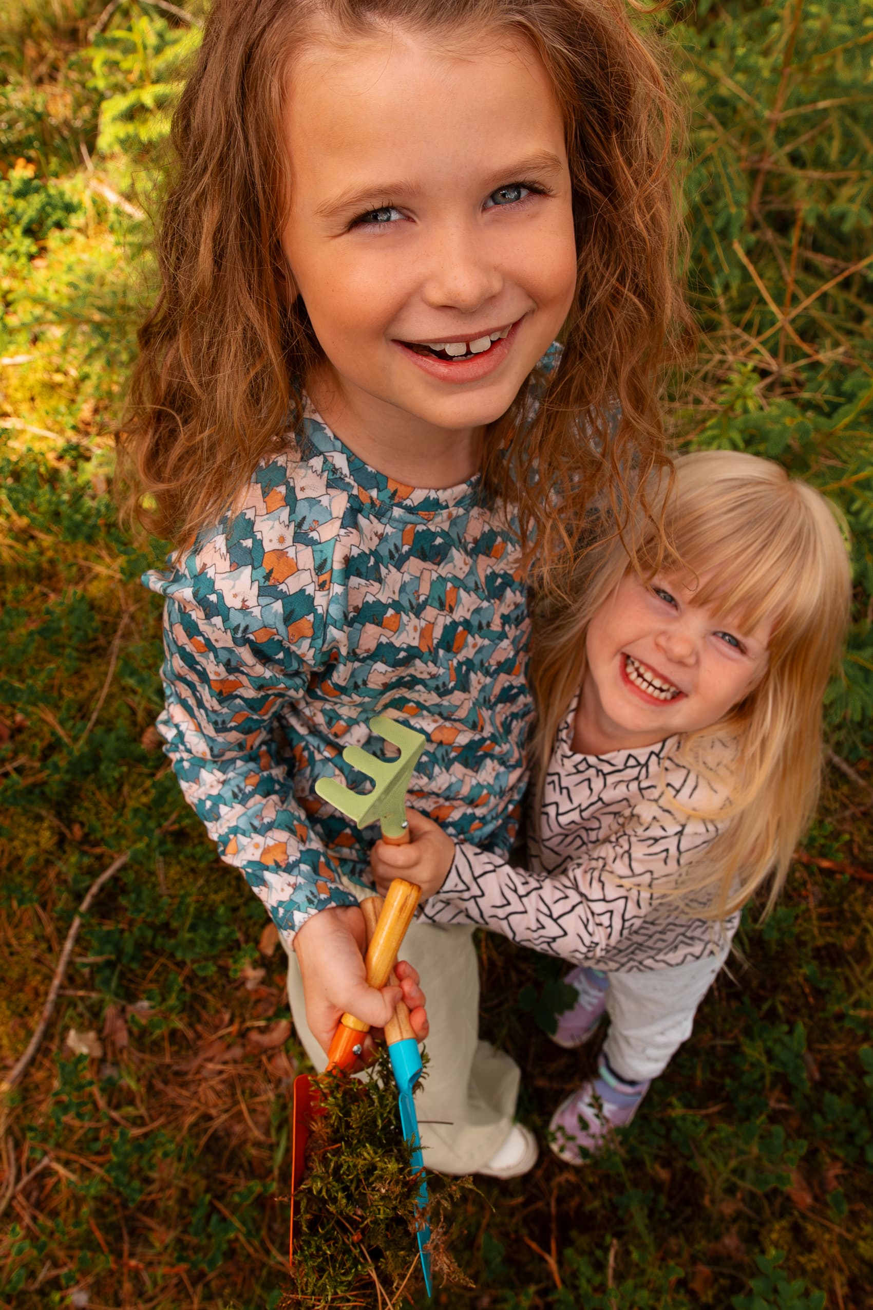 Zwei Mädchen tragen Merino Kinder-Langarmshirts von Bellibell und spielen gemeinsam im Wald.